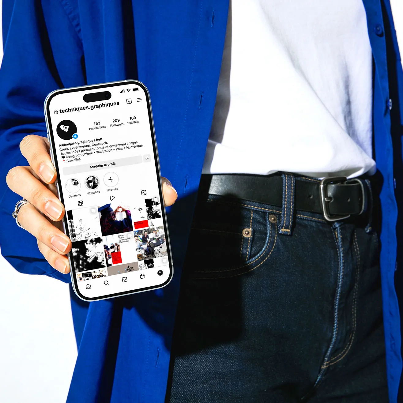Main tenant un smartphone affichant le profil Instagram de la section Techniques Graphiques